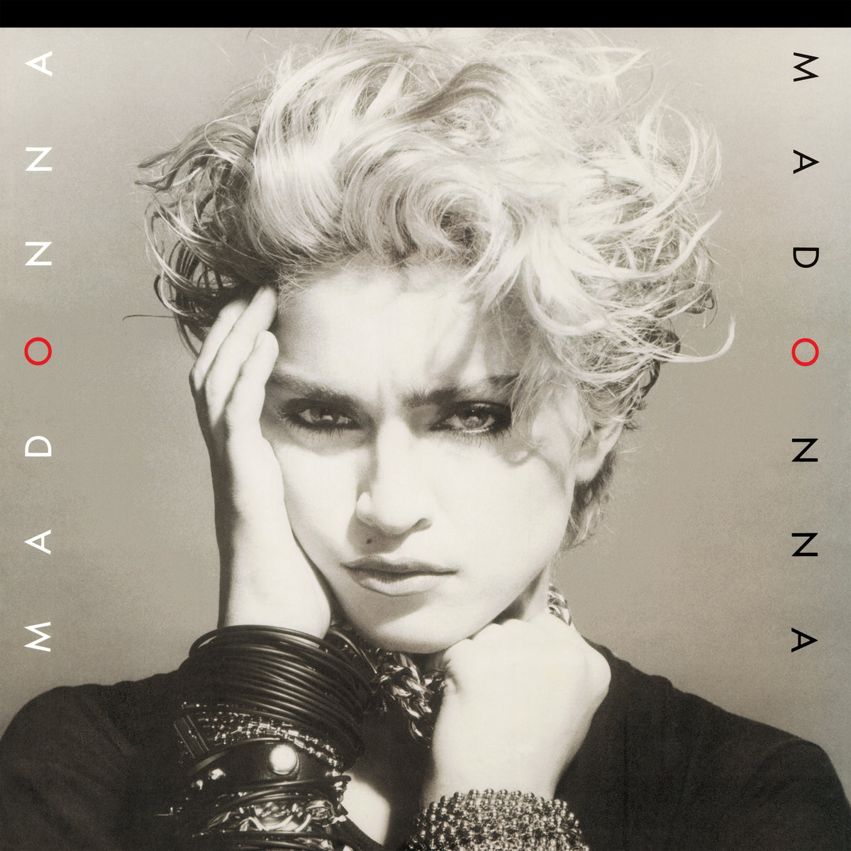 Album cover art for Madonna featuring a black and white close-up portrait of Madonna with stylized hair and text reading 'MADONNA' vertically along the sides.